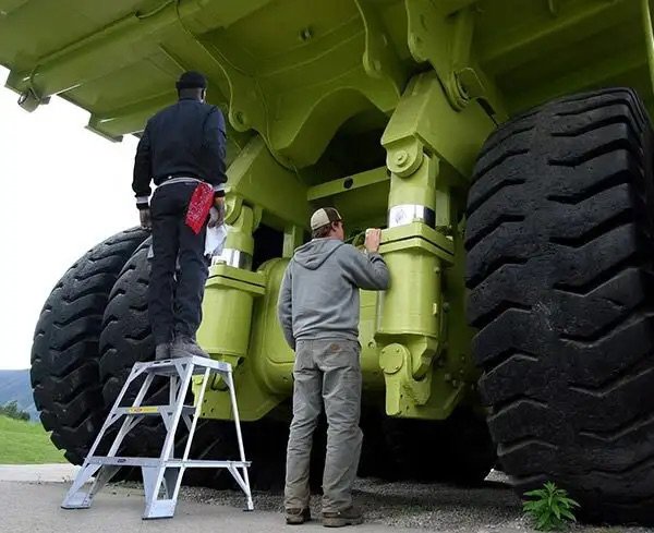 Workers using a portable ladder during equipment maintenance