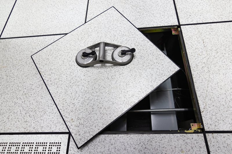 A tile being removed from a low-profile raised floor system in a data center.