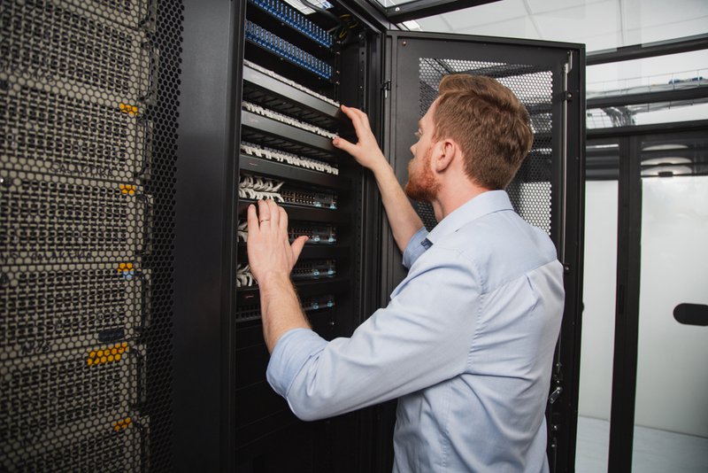 Data center consultants reviewing infrastructure scalability plans and airflow management layouts inside a modern server facility.