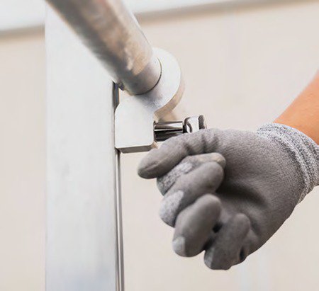 A close up image of a hand holding an aluminum railing.