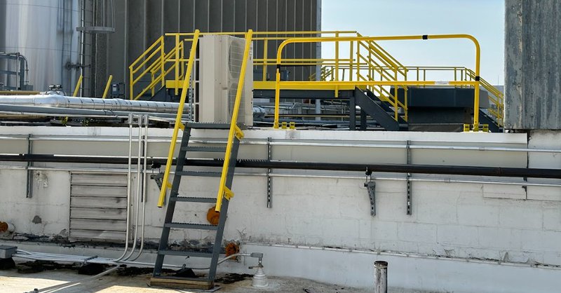 Yellow aluminum railing for stairs on a NextGen crossover platform at an industrial rooftop facility