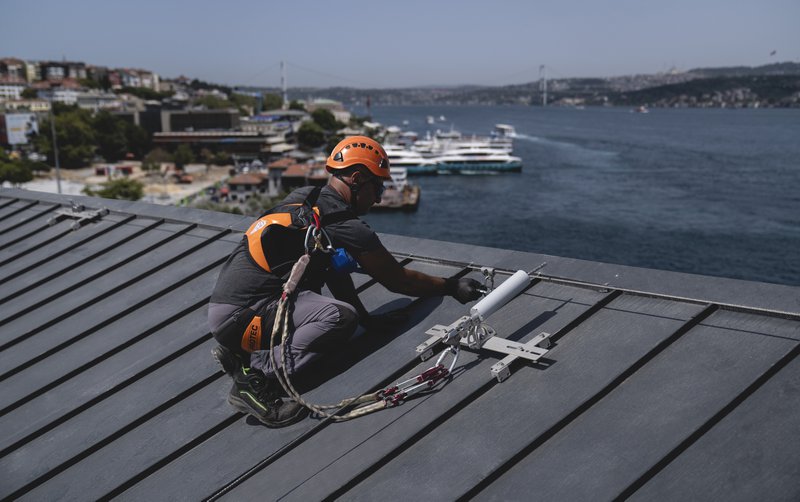 The image shows a worker wearing a safety harness fall protection equipment
