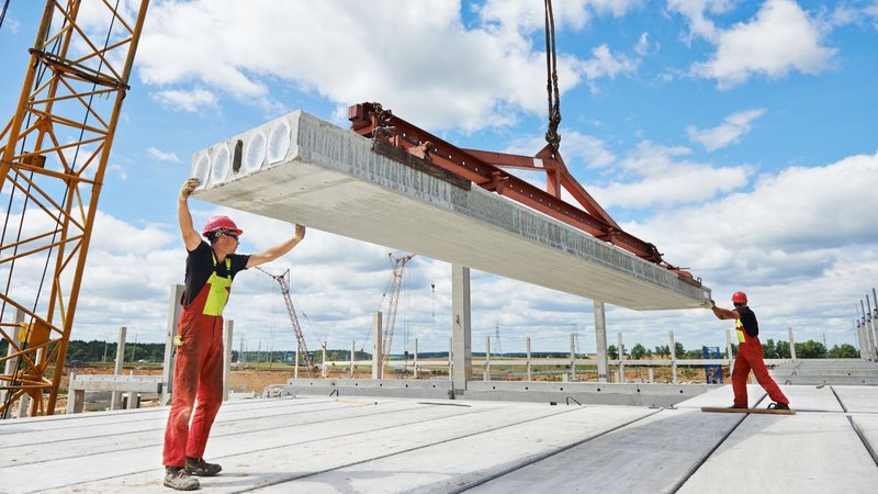 Workers guiding a concrete slab at a construction site assessing the U Value of Wood.