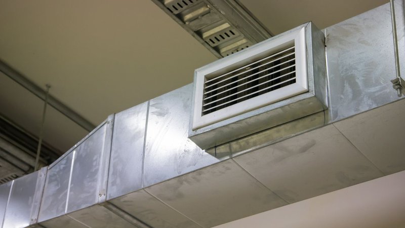 A close-up of a ceiling-mounted silver ventilation duct for forced draft systems.