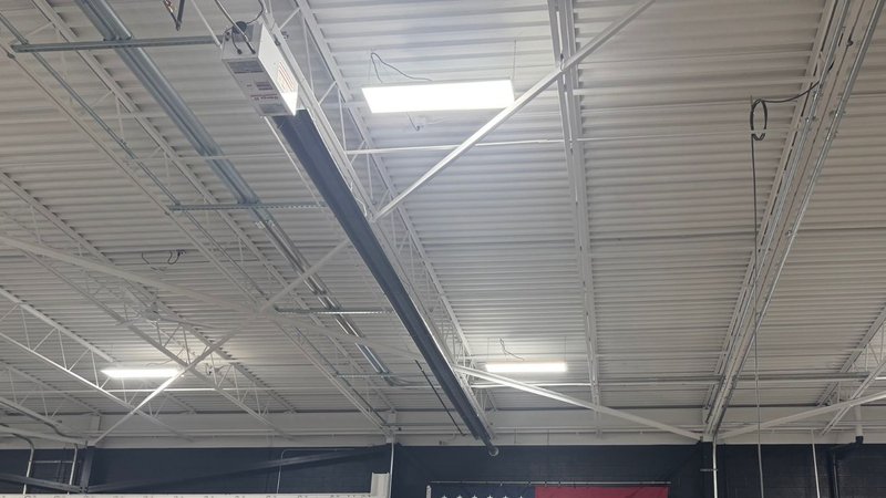 A white corrugated metal ceiling with exposed steel beams configured for forced draft systems