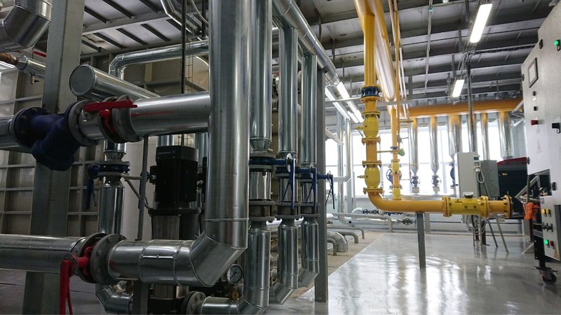 A complex network of industrial piping and valves regulating a plant's spot heating system.