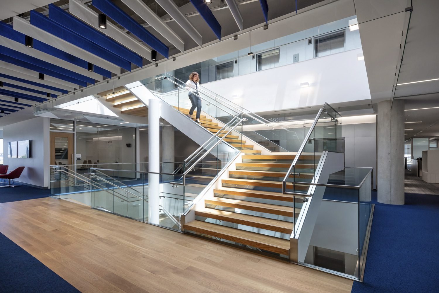 Corporate office stairwell that uses white oak treads and glass risers