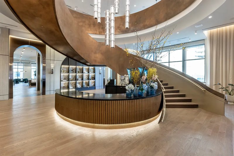 The image shows an elegant stairway, a posh reception desk, and a neatly installed hardwood flooring