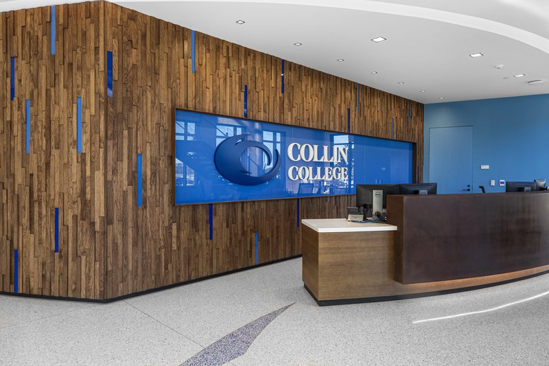 This photo features a reception desk with a striking wooden wall as the centerpiece.