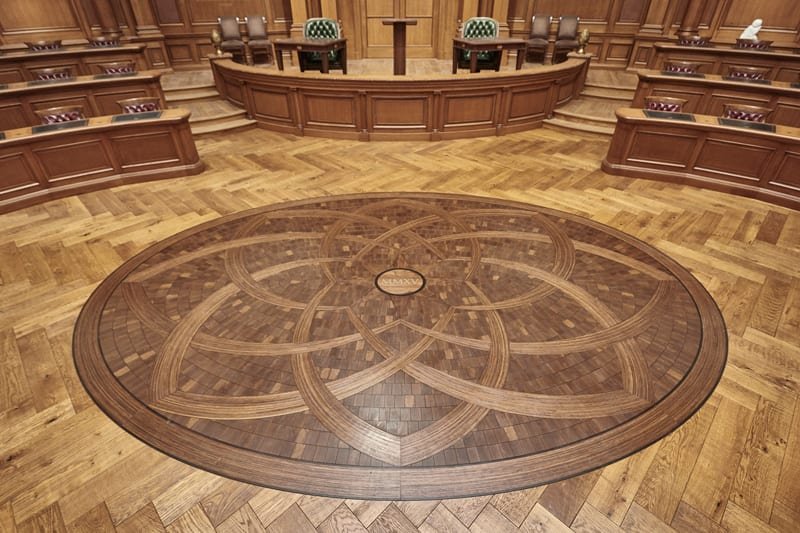 The image shows a handcrafted medallion designed by Woodwright as part of their professional hardwood floor installation for the Old Parkland Campus in Dallas, Texas. The image shows a handcrafted medallion designed by Woodwright as part of their professional hardwood floor installation for the Old Parkland Campus in Dallas, Texas.