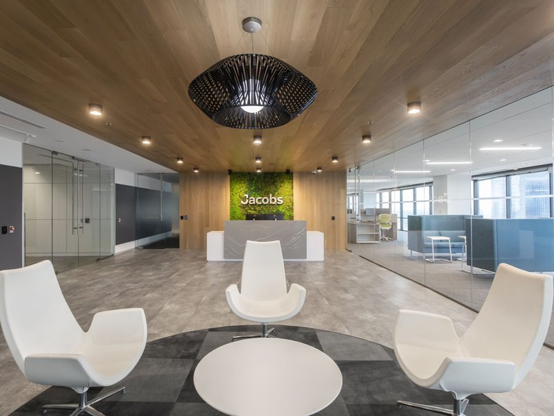 The image shows the use of European Oak in a corporate office. The image shows three chairs, a circular table, and a logo of Jacobs