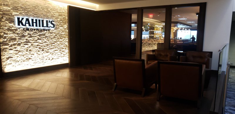 The image shows an interior office that uses real wood flooring. Some sofas and a 3D wall that's brightly light can be seen in the photo.