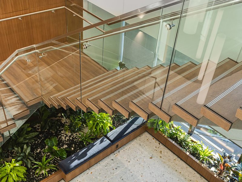 The image shows a monumental staircase that has a 3-inch thick engineered box treads crafted from Rift White Oak.