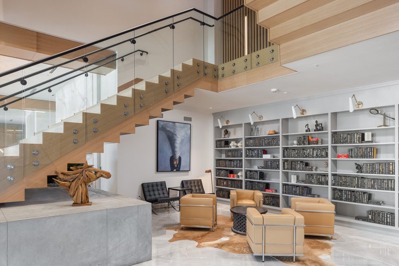 The image shows several sofas and bookcases. The interior is accentuated by luxury stairs made by Woodwright.
