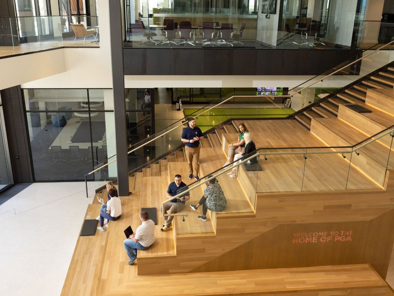 A photo showing people inside the PGA building sitting on hardwood flooring. 
