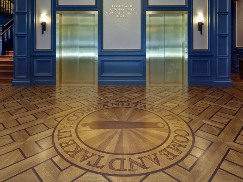 This photo features flooring with an inlay that shows how custom wood fabrication can display brand identity