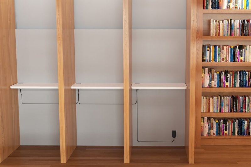 Desks with recessed outlets right next to a bookshelf