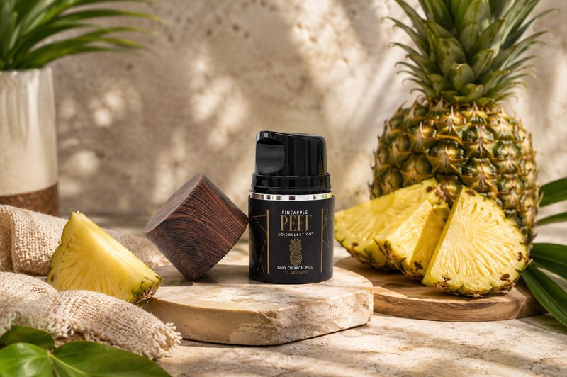Pineapple Peel anti aging exfoliator surrounded by fresh pineapple slices in a tropical skincare setting.