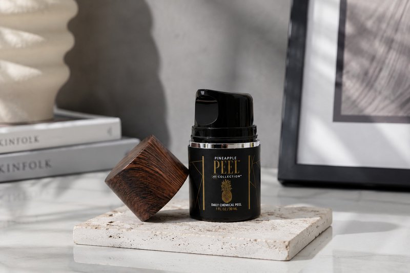 Pineapple Peel anti aging exfoliator displayed on a stone surface in a modern skincare setting.