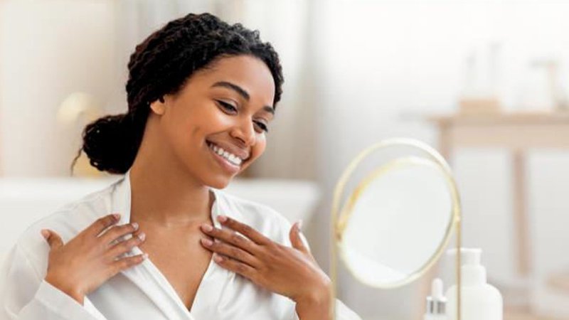 A woman using AHA Exfoliator on neck and chest area.