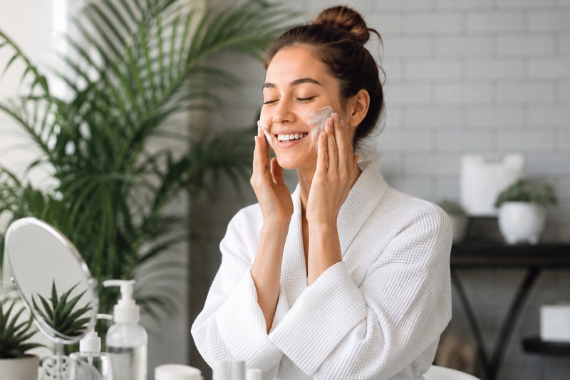 A woman applying skin care to combat weak skin barrier