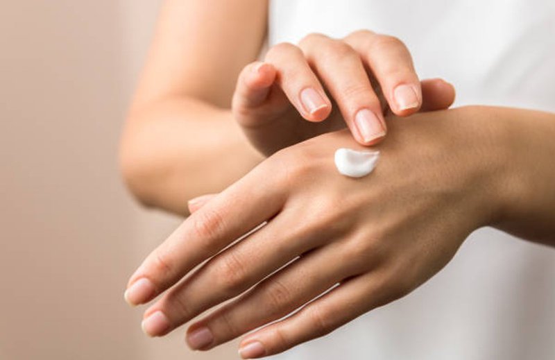 Close-up of a woman applying hand cream to the back of her hand
