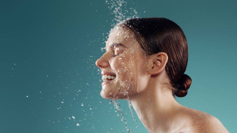 woman rinsing her face with water in preparation for her nighttime skincare routine