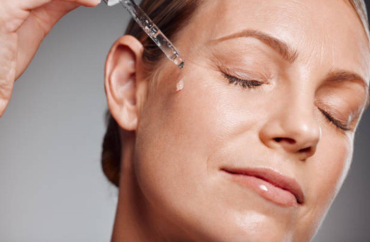 Middle-aged woman applying vitamin C serum