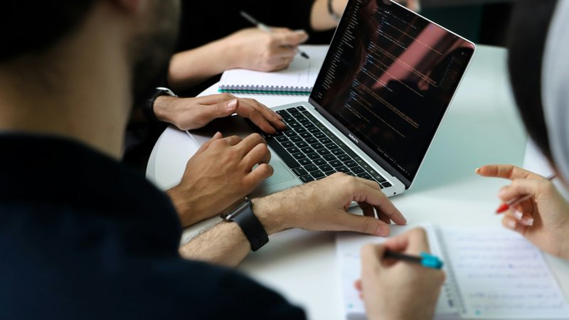 a group of people discussing while looking into a laptop. Netsuite Solutions