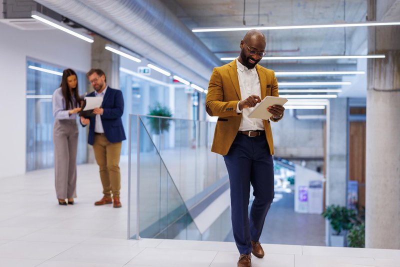 Business executive accessing real-time performance reports on a tablet while moving through the office.