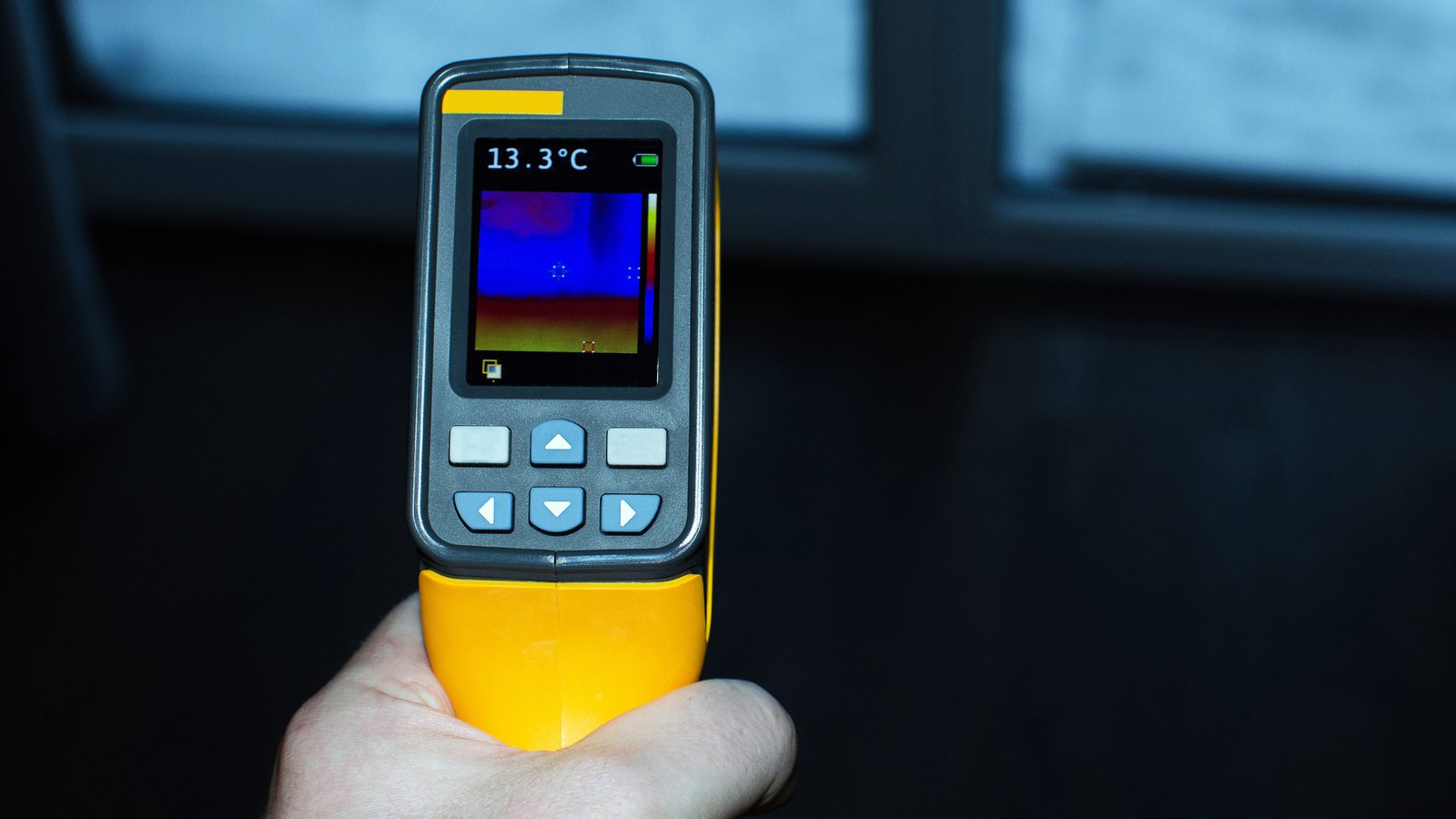 Close up of inspector's hand using thermal imaging to identify concealed conditions during renovation