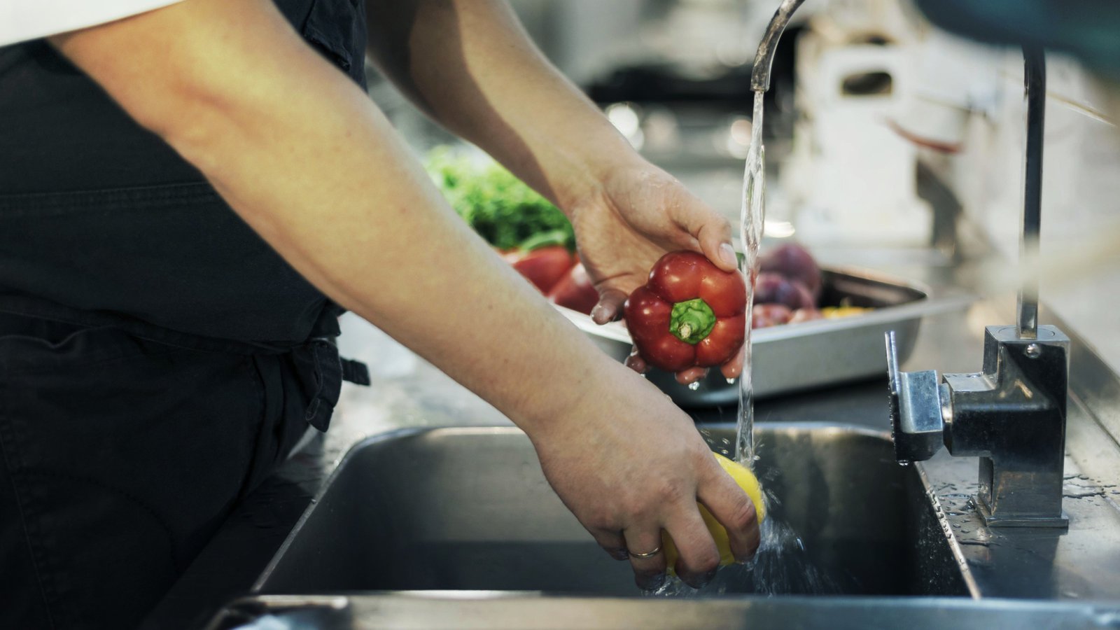 Chef washing fresh ingredients with clean water in a commercial restaurant kitchen