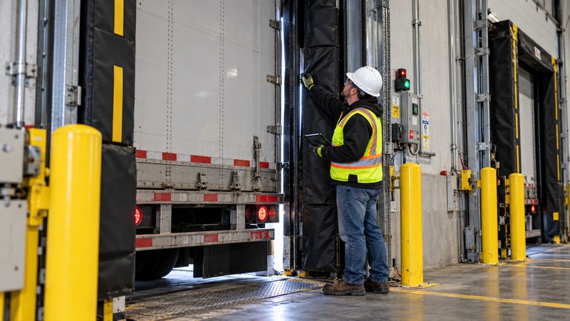Facility technician inspecting loading dock seals for air gaps and energy loss