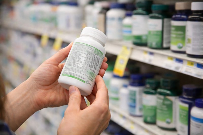 Person closely examining a supplement label in a store aisle