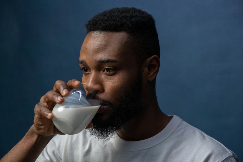 This photo features a man drinking milk 