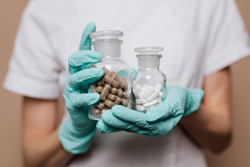 This photo shows a pharmacist holding supplements in bottles