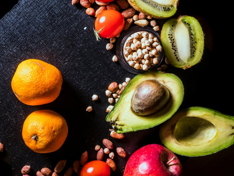 This photo shows oranges, avocados, tomatoes, and other superfoods on a black background