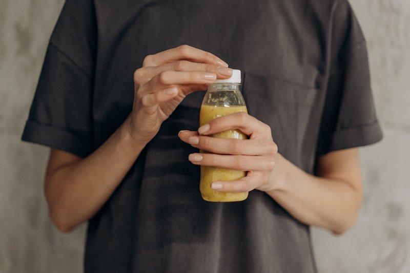 This photo features a person opening a bottle of probiotic drink
