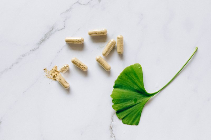 This photo shows a green gingko leaf next to capsules of plant-based supplements 