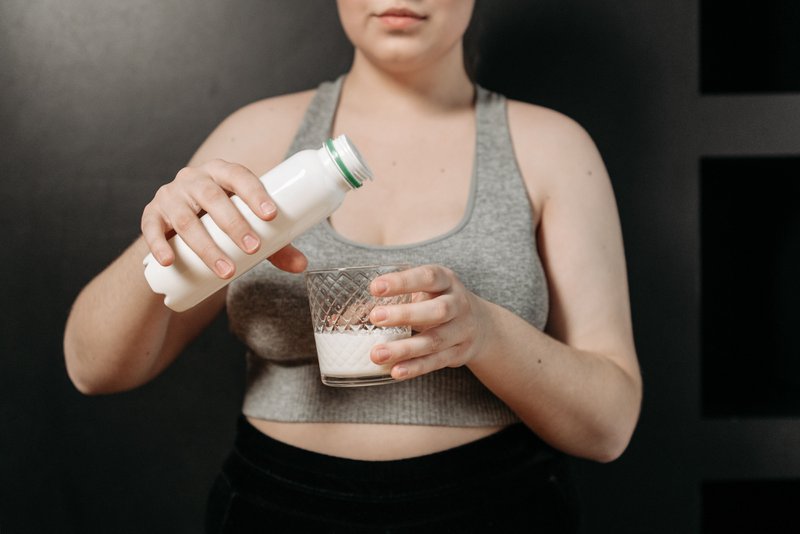 This photo features a woman pouring a probiotic drink into a glass