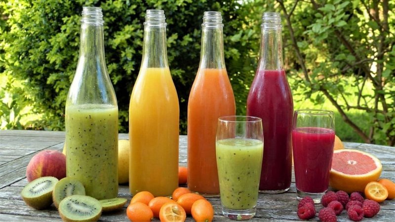 Colorful juice in a Beverage Bottle surrounded by fresh fruit.