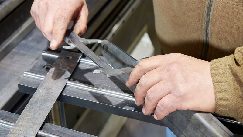 A steel worker measuring slim profile HSS columns