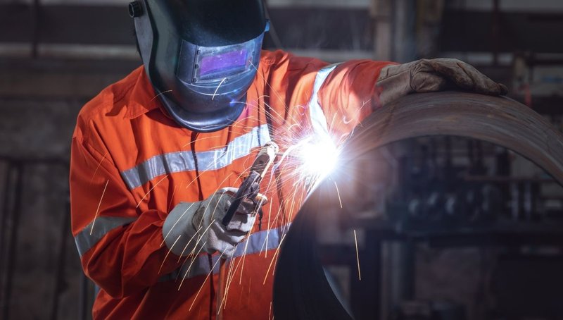 Effective Deep Foundation Engineering Strategies Using Steel Pipe Piling 1 A welder working on a large steel tube used in Pipe Piling construction.