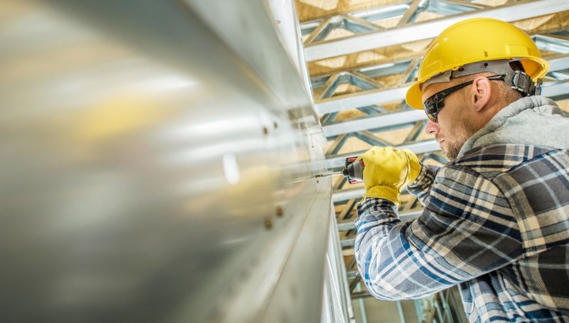 Why HSS Steel Is the Gold Standard for Seismic Resilience 2 A construction worker drilling into a metal surface during the installation of HSS steel.
