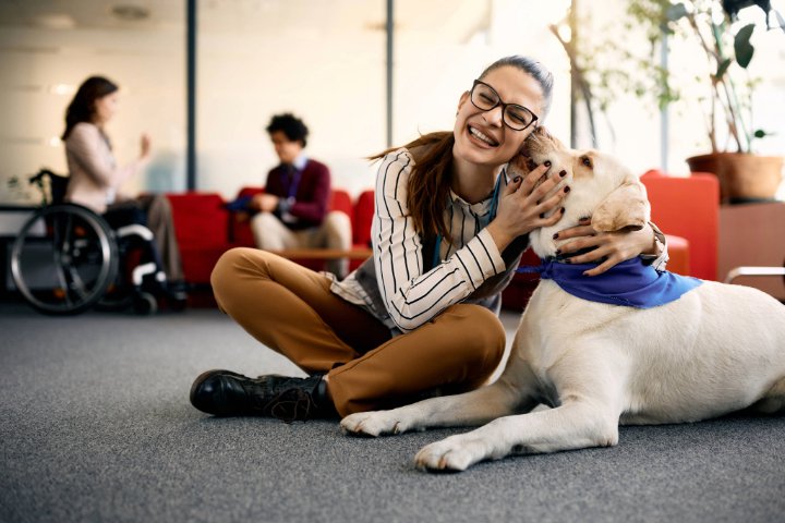 Dog licking the face of a woman while sitting on the floor