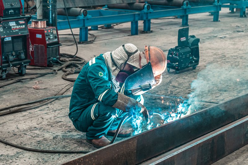A welder on duty, with the work clamp connected to the welding machine via a welding cable.