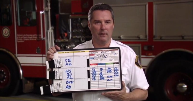 Fire official holding an incident command board near a fire truck.