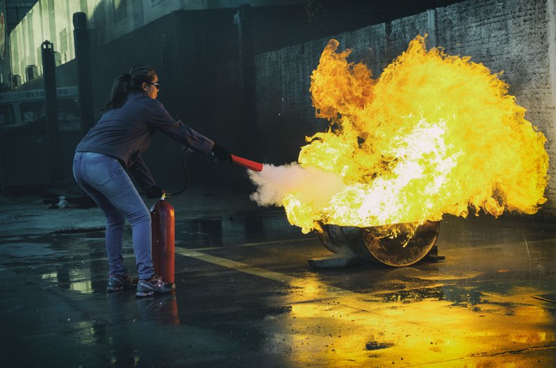 A woman operating a fire extinguisher as part of fire drills.