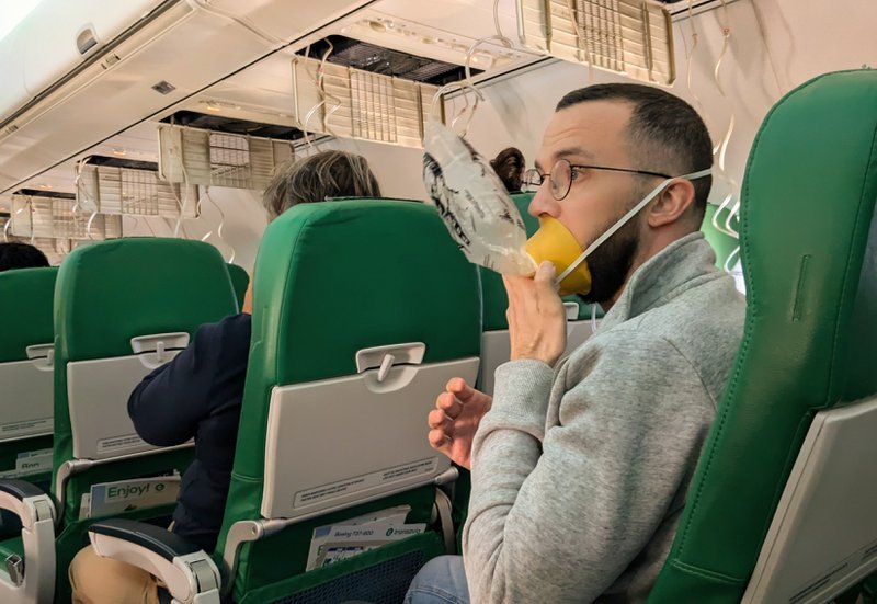 An airplane passenger using an oxygen mask, a potentially life-threatening emergency that requires quick incident response time.