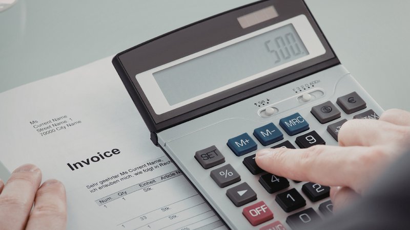 Business owner reviewing invoices and calculating working capital requirements.